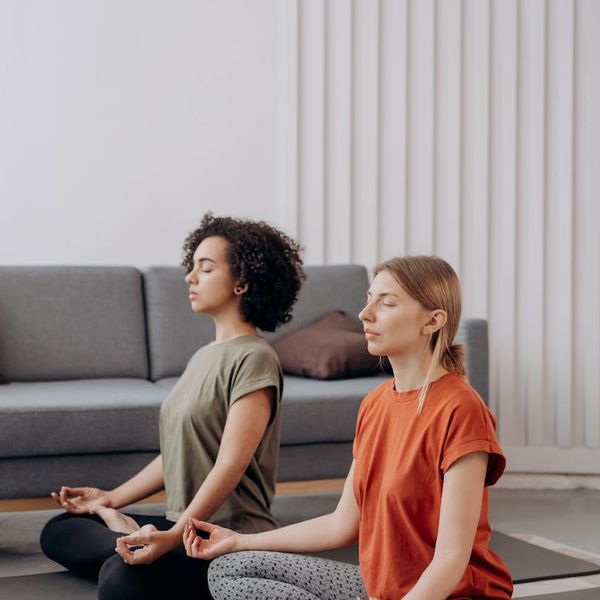 Woman practicing a gentle yoga pose in a bright, calm room.